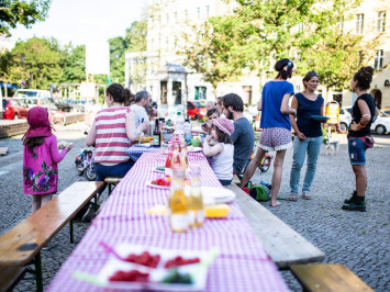 Auf dem Tuchollaplatz in Berlin wird eine lange Tafel für den Tag der Nachbarn aufgebaut (Bild: Christian Klant/ nebenan.de Stiftung)